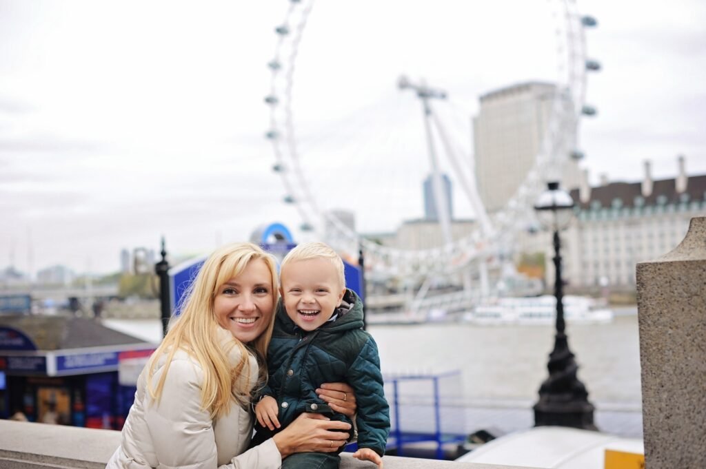 Happy mother and son laughing in front of London Eye wheel. Family vacation in the UK